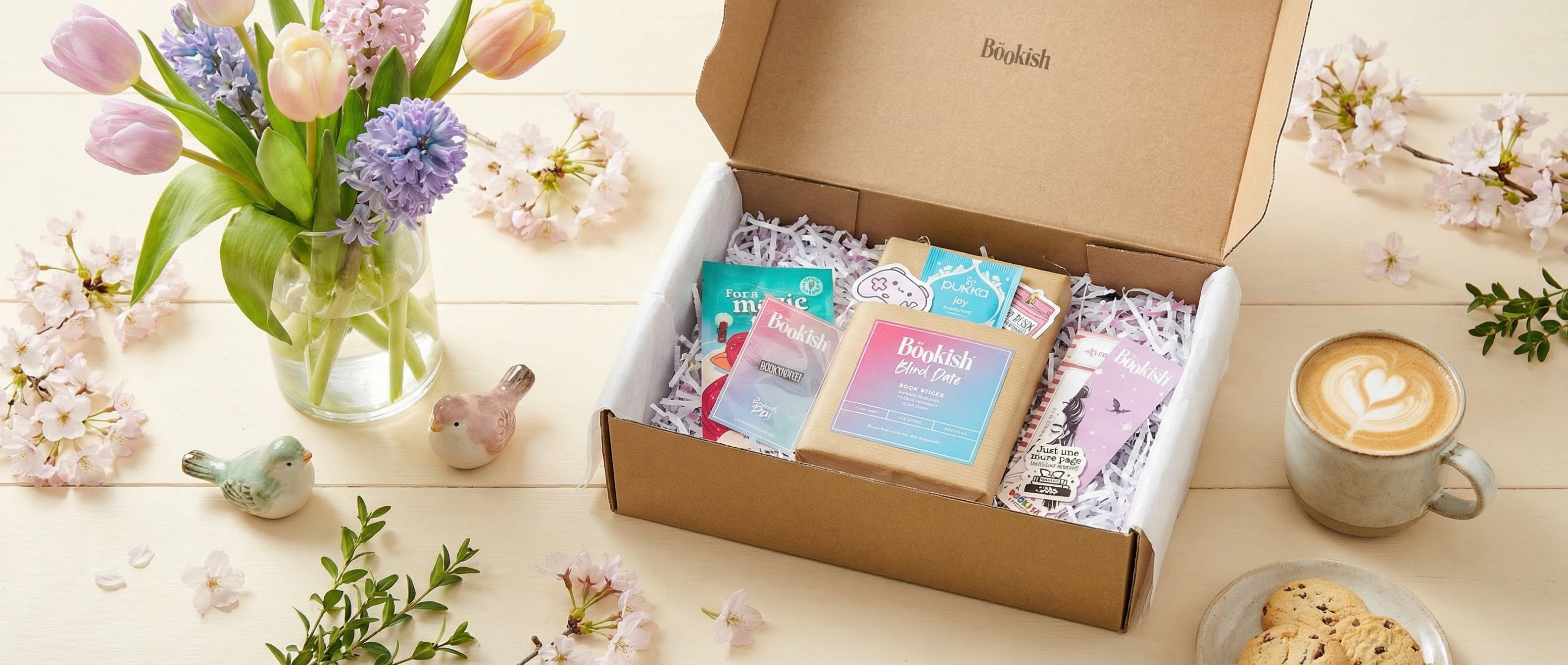 Be Bookish® Blind Date Box umgeben von Frühlingsdeko wie Blumen und hellen Farben für eine cozy, saisonale Leseatmosphäre